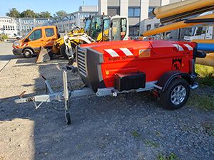 Orangefarbener Spillwinde Anhänger steht auf einem Parkplatz.