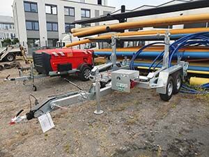  Ein Abrollanhänger steht vor einem Rohrlager.