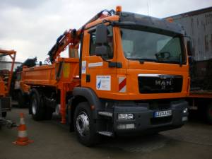 Ein großer orangefarbener Kranwagen steht auf der Baustelle.