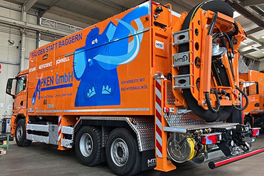 Ein großer orangefarbener Saugwagen von hinten.