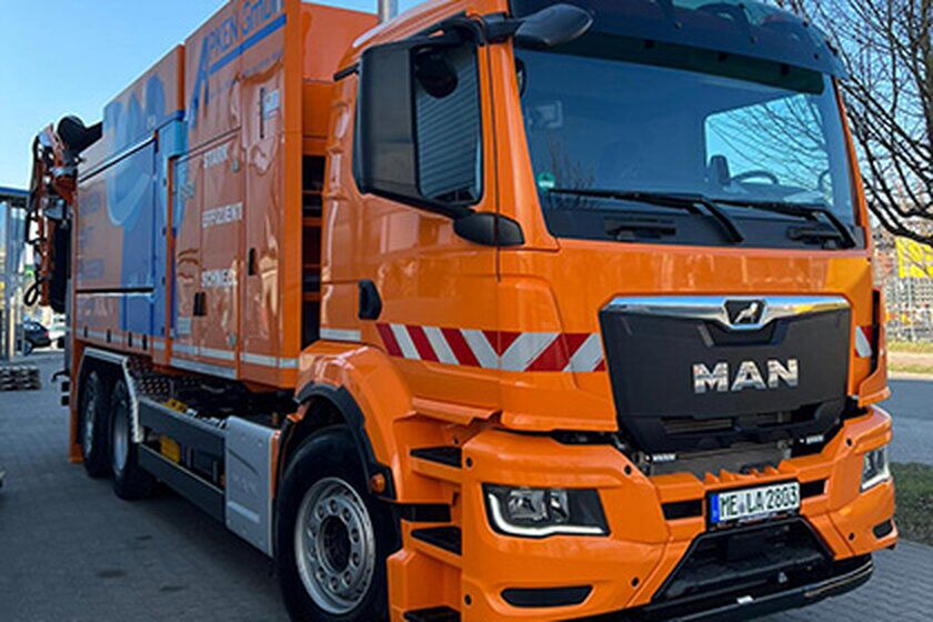 Ein großer orangefarbener Saugwagen von vorne.