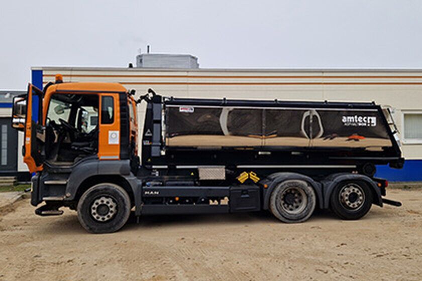 Ein großer Thermocontainer mit offener Tür steht vor einem Gebäude.